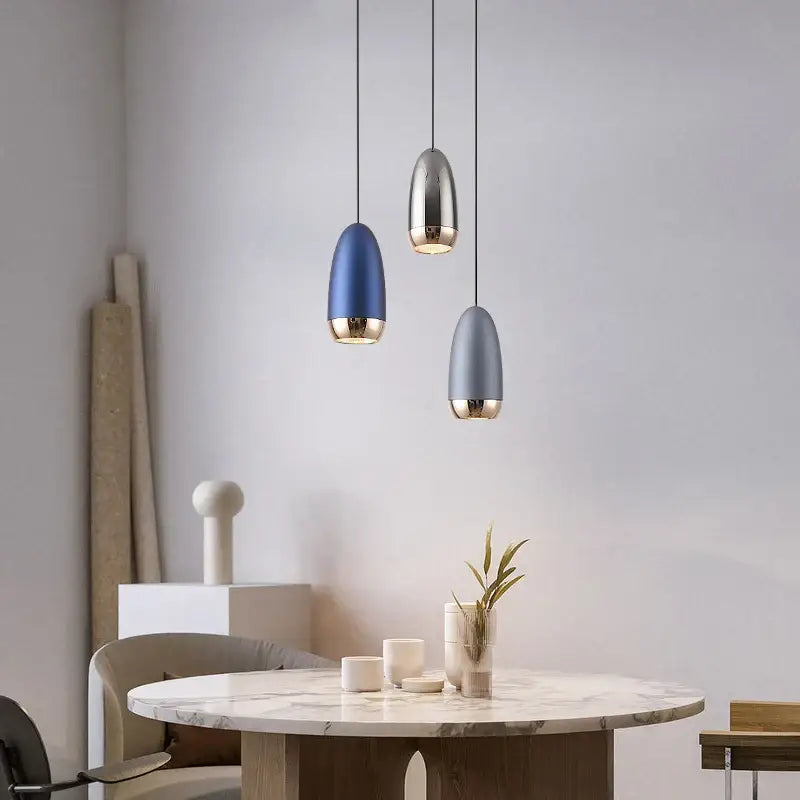 Three decorbites led pendant lights with teardrop blue silver gray shades and gold accents for modern interiors