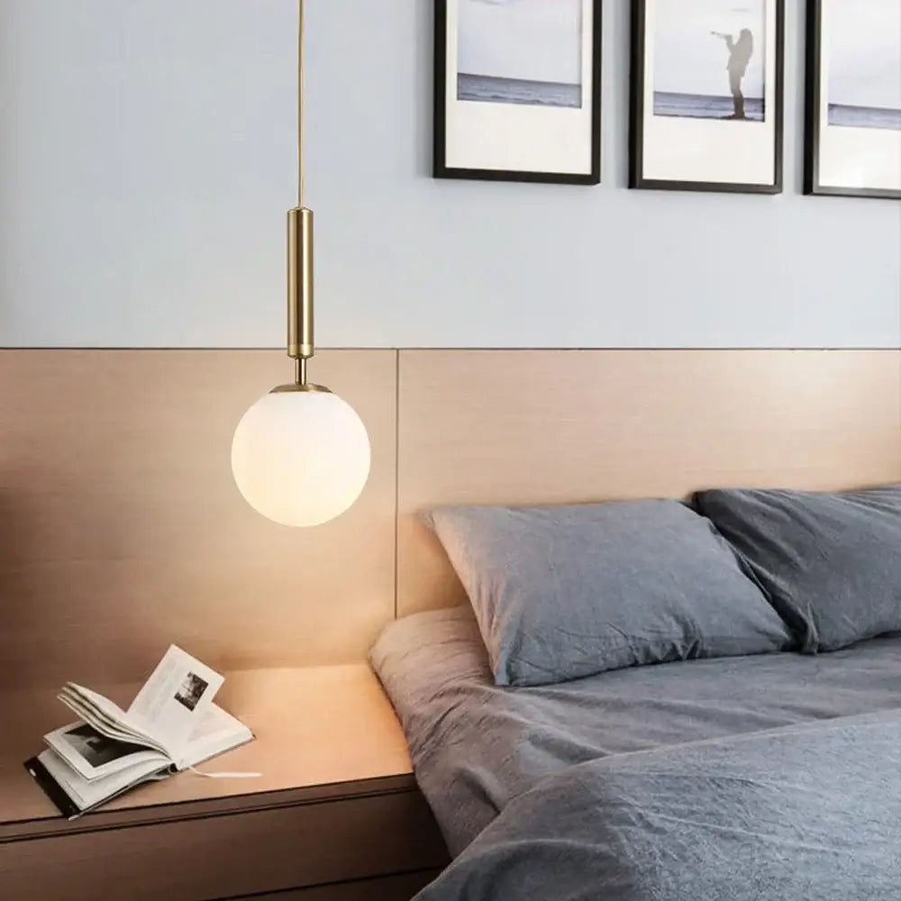 A modern decorbites led pendant light with brass cylindrical stem and frosted glass globe shade for dining room
