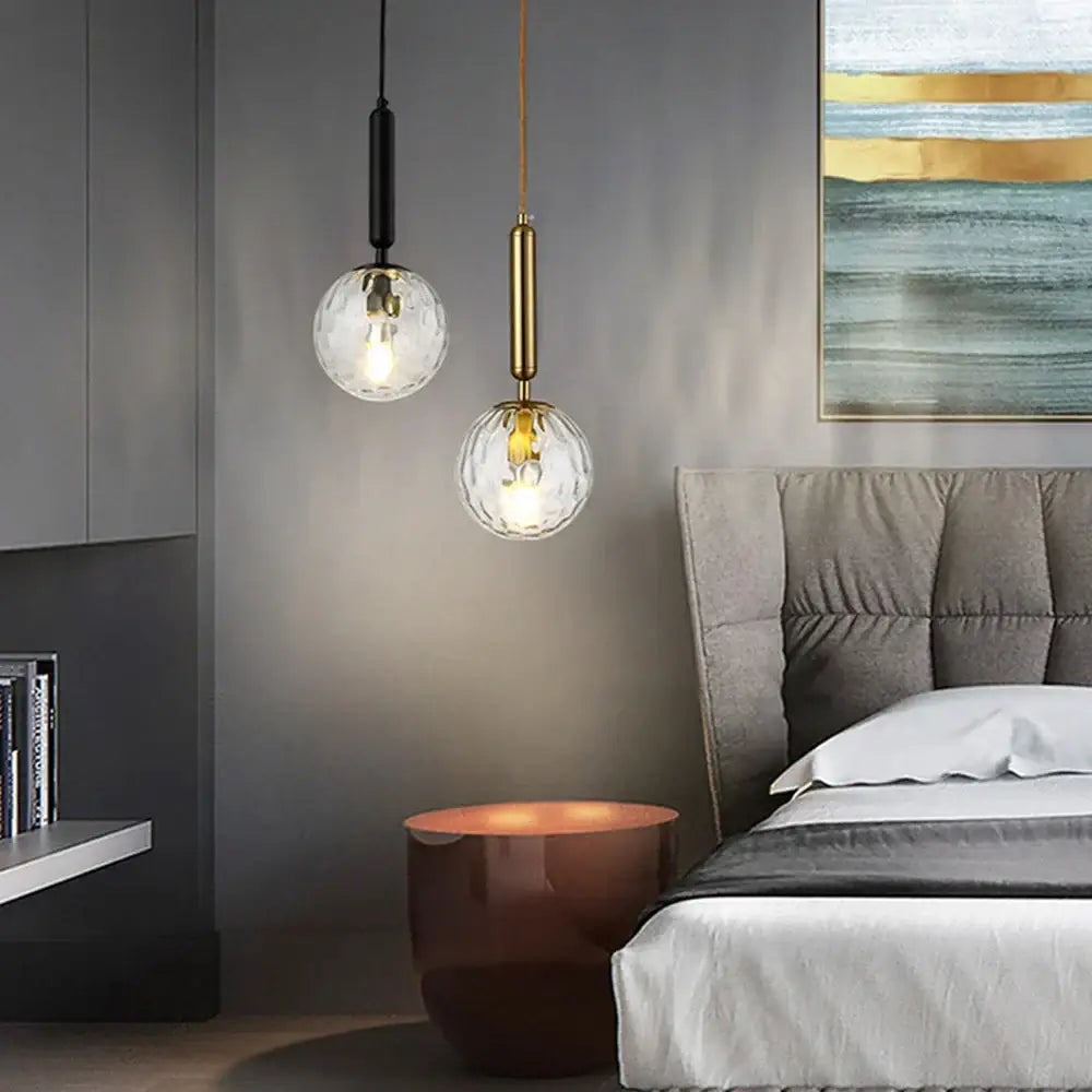 Two modern decorbites led pendant lights with faceted glass globes and metallic stems in black and gold for dining room