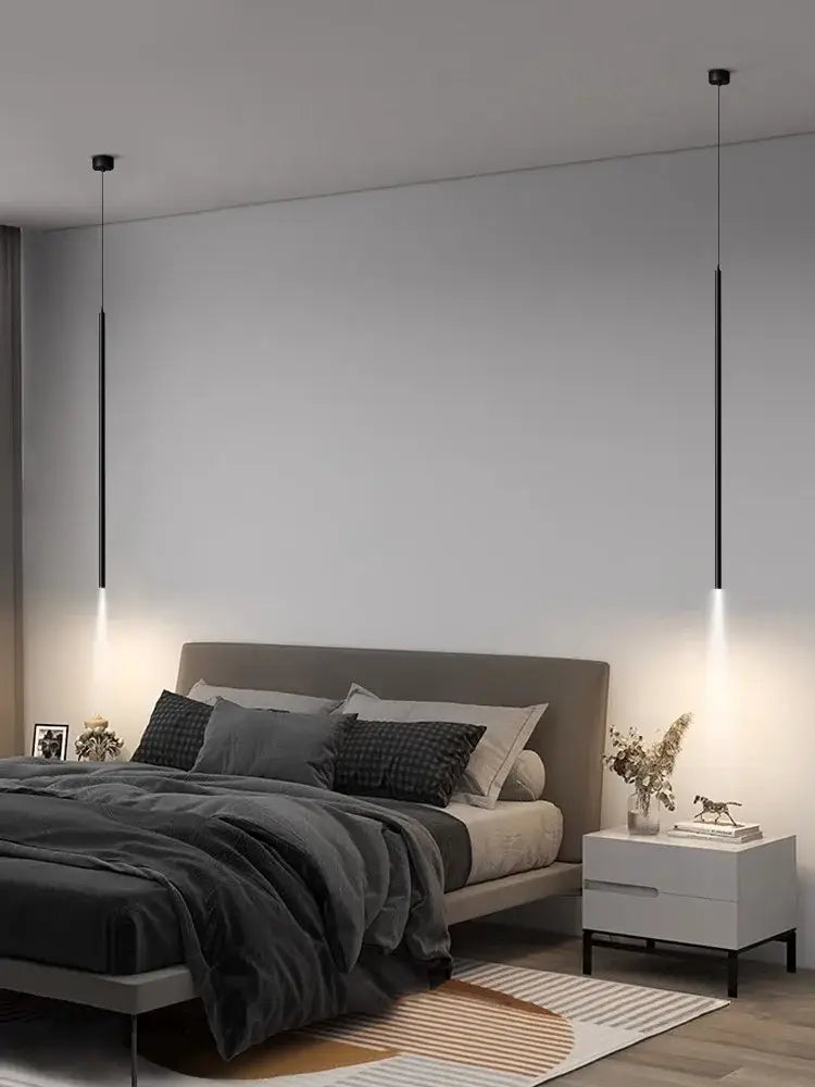 Two sleek black DecorBites led pendant lights with slim cylindrical bodies hang symmetrically above the bed