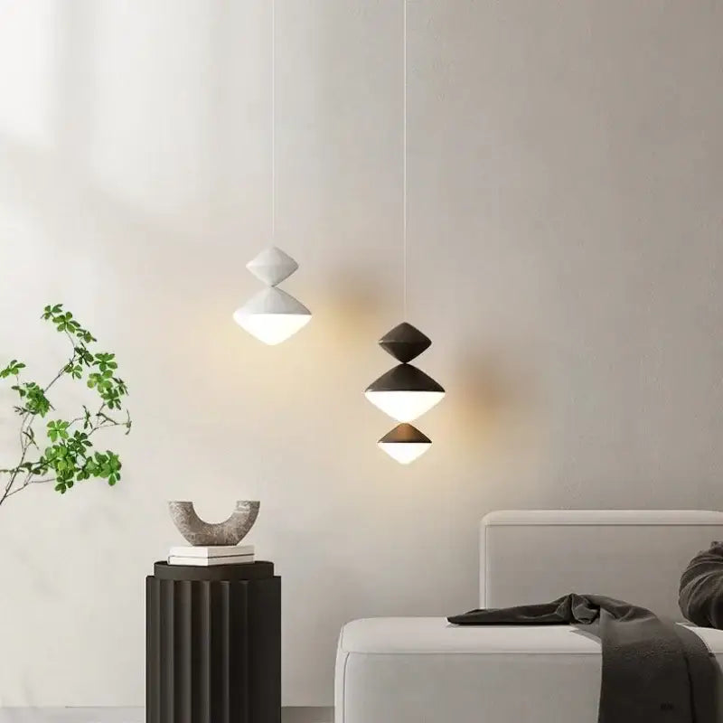 Two modern pendant lights with black and white geometric stacked cone designs and warm glow from decorbites led pendant lights