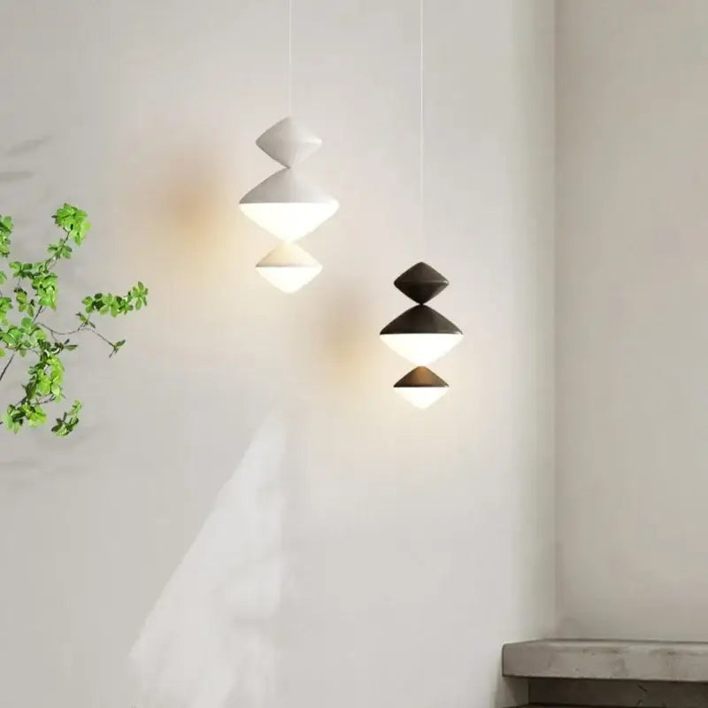 Modern geometric DecorBites led pendant lights with stacked white and black triangular shades emitting warm glow