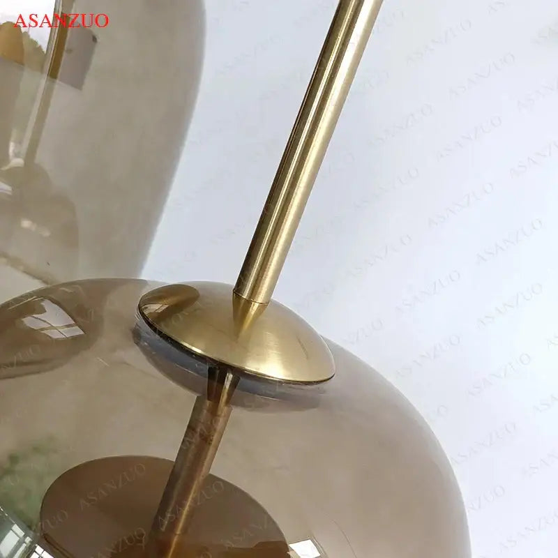 Gold-toned metal rod with polished finish connects to translucent amber globe in decorbites led pendant lights modern design