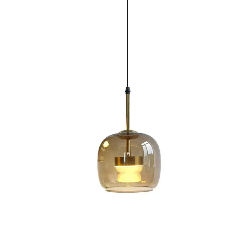 A modern amber glass decorbites led pendant light with brass finish metal stem for home decor lighting