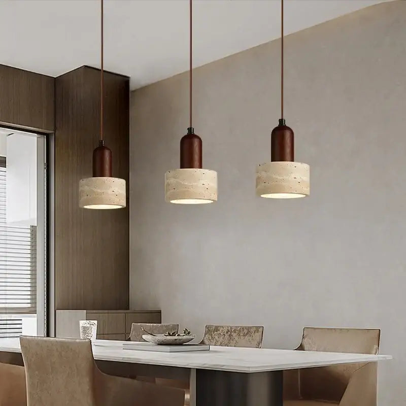 Three decorbites led pendant lights with dark brown metal tops and textured beige concrete shades above dining table