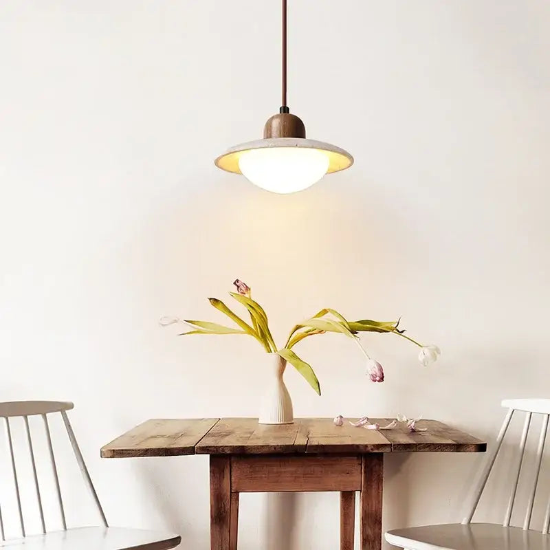 Warm-toned DecorBites™ LED pendant light with wooden top and frosted glass shade hanging above rustic table