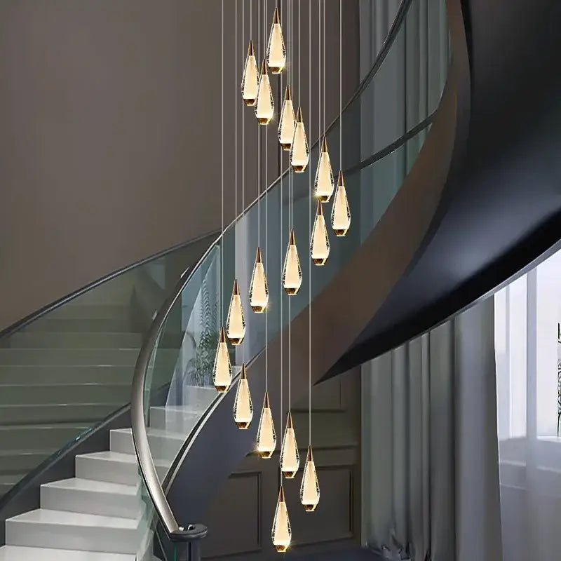 A modern decorbites led pendant staircase chandelier with teardrop crystal pendants and gold-toned caps emitting warm light