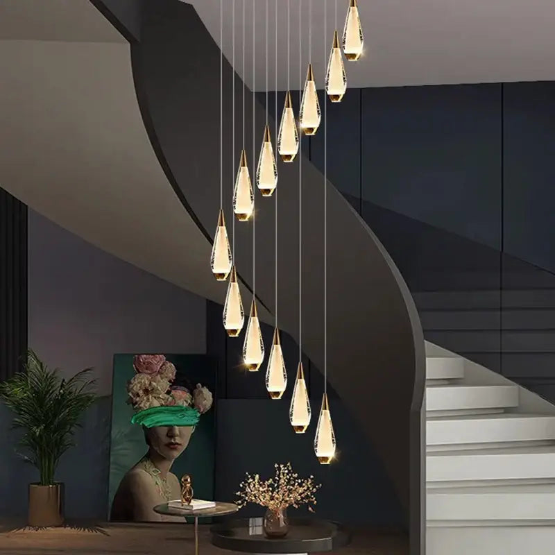 A modern decorbites led pendant chandelier with teardrop crystal pendants and gold-toned bases for staircase lighting
