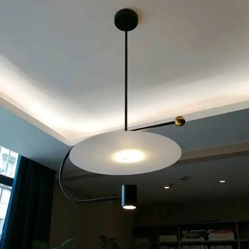 Decorbites™ pendant light fixture with matte black mount, brass sphere, and frosted white disc shade for indoor use