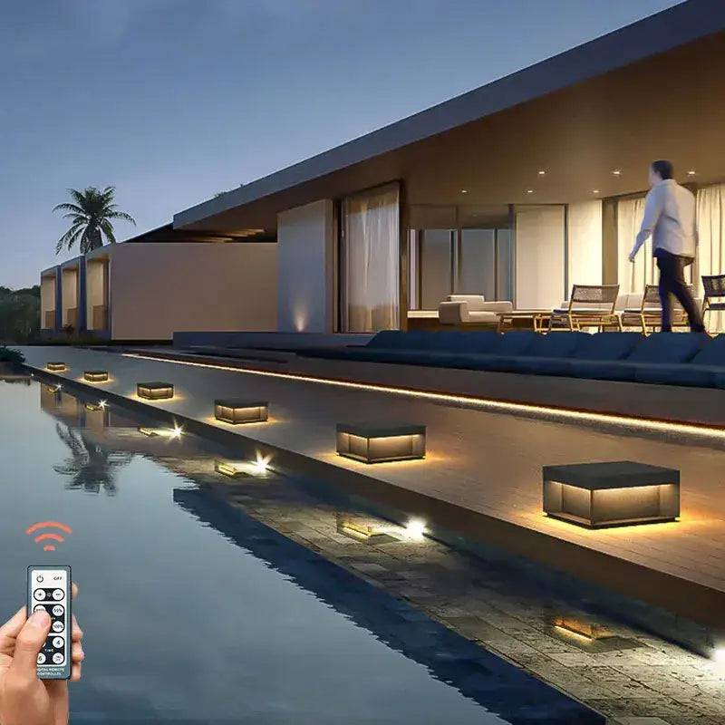 Black rectangular DecorBites led pillar top courtyard lights with warm glow along poolside deck outdoor pathway