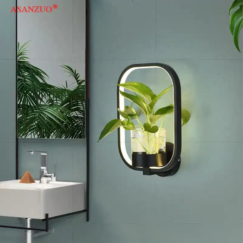 Black-framed oval decorbites led plant wall lamp with integrated led and clear glass vase holding green foliage