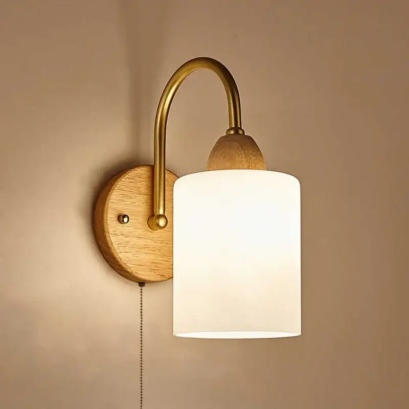 A warm-toned decorbites led pull chain wall light with brass arm, wooden backplate, and frosted white glass shade for bedroom