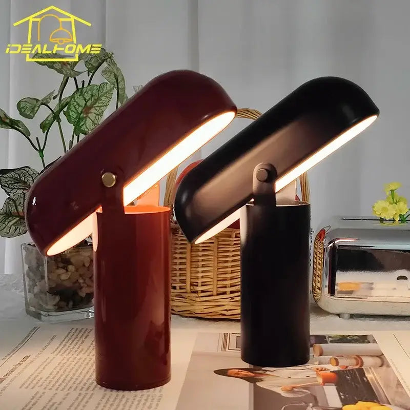 Two sleek decorbites led rechargeable table lamps with glossy burgundy and matte black finishes emitting warm light