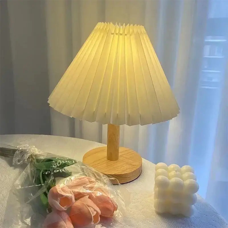 A cream-colored pleated lampshade with wooden base on a decorbites led retro table lamp for interior lighting