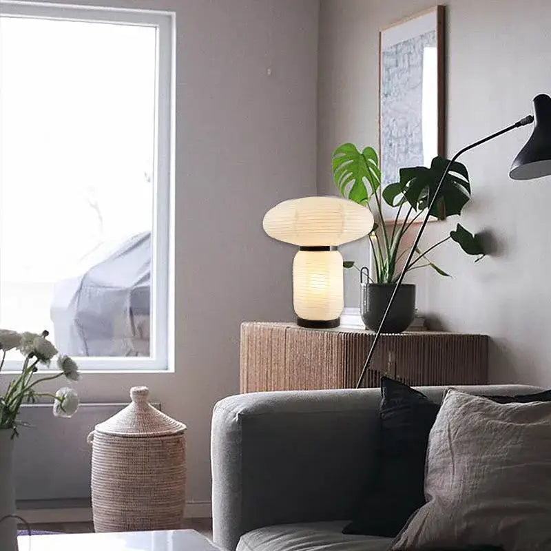 A warm glowing decorbites led rice paper table lamp with paper lantern shade and ribbed cylindrical base