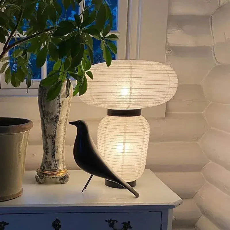 A sleek black ceramic bird figurine beside a decorbites led rice paper table lamp with minimalist modern design