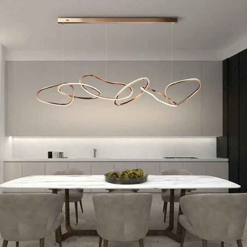 Modern gold-toned abstract decorbites led ring chandelier with interlocking loop design above marble dining table