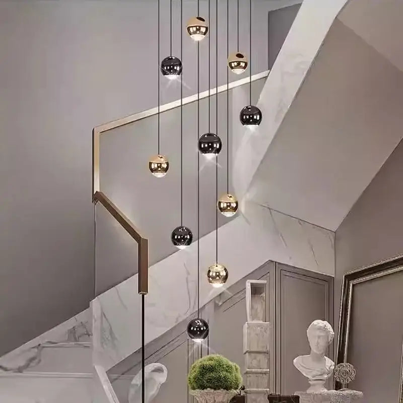 Modern pendant lights with spherical reflective black and gold orbs hanging from slender cords with heads size diameter