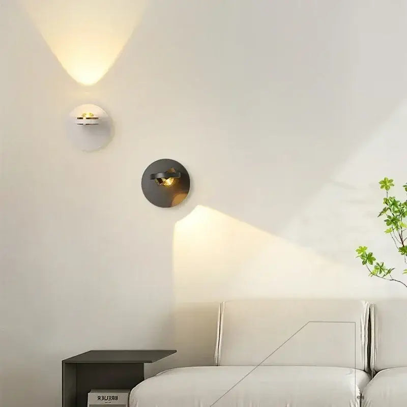 Two minimalist decorbites™ led rotatable wall lamps with matte white and dark metal bases emitting warm light