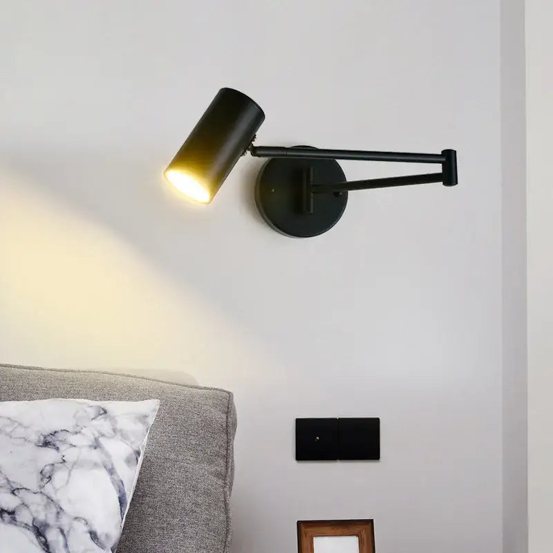 Black matte LED rotatable wall lamp with cylindrical gold-black metal sconce head emitting warm light