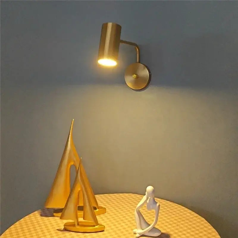 Gold-toned DecorBites™ LED rotatable wall lamp with sleek cylindrical head and circular base for modern lighting