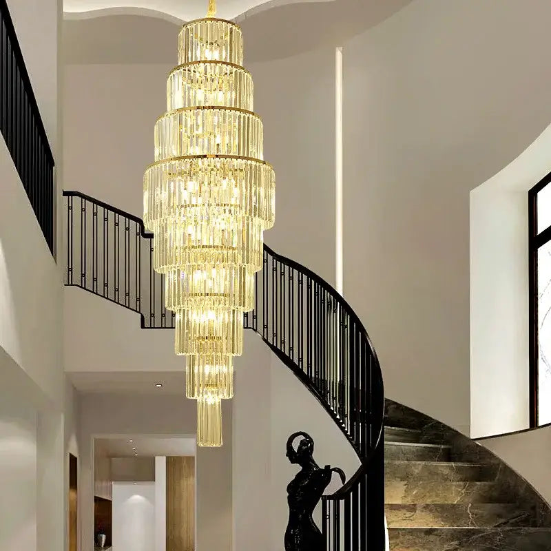 Golden tiered crystal decorbites™ led rotating staircase chandelier hanging above a spiral staircase for duplex living