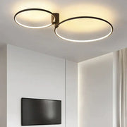 Modern black led round ceiling lamp with two interlocking rings emitting warm glow in white black gold aluminum