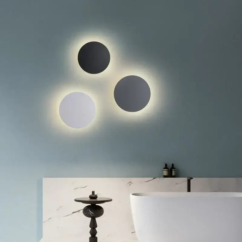 Three decorbites led round touch wall lamps with black and white faces mounted on a muted blue wall for bedroom decor
