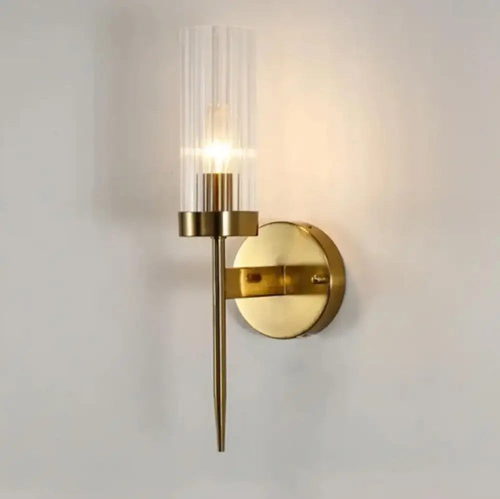 Modern brass decorbites led sconce with cylindrical ridged glass shade and illuminated bulb for bedroom and home use