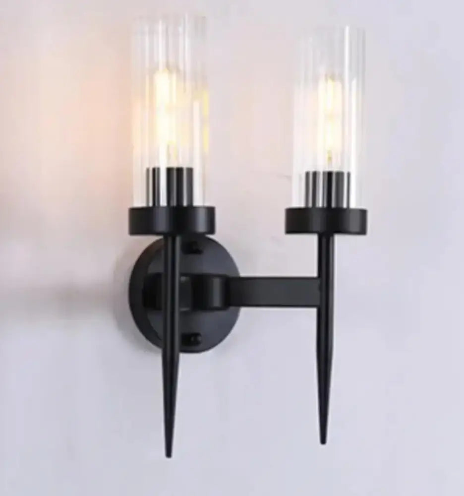 Black metal decorbites led sconce with two clear glass cylinders and exposed filament bulbs for modern bedroom lighting