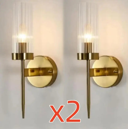 Gold-toned decorbites led sconce with cylindrical glass shade and slender metal stem for modern bedroom lighting