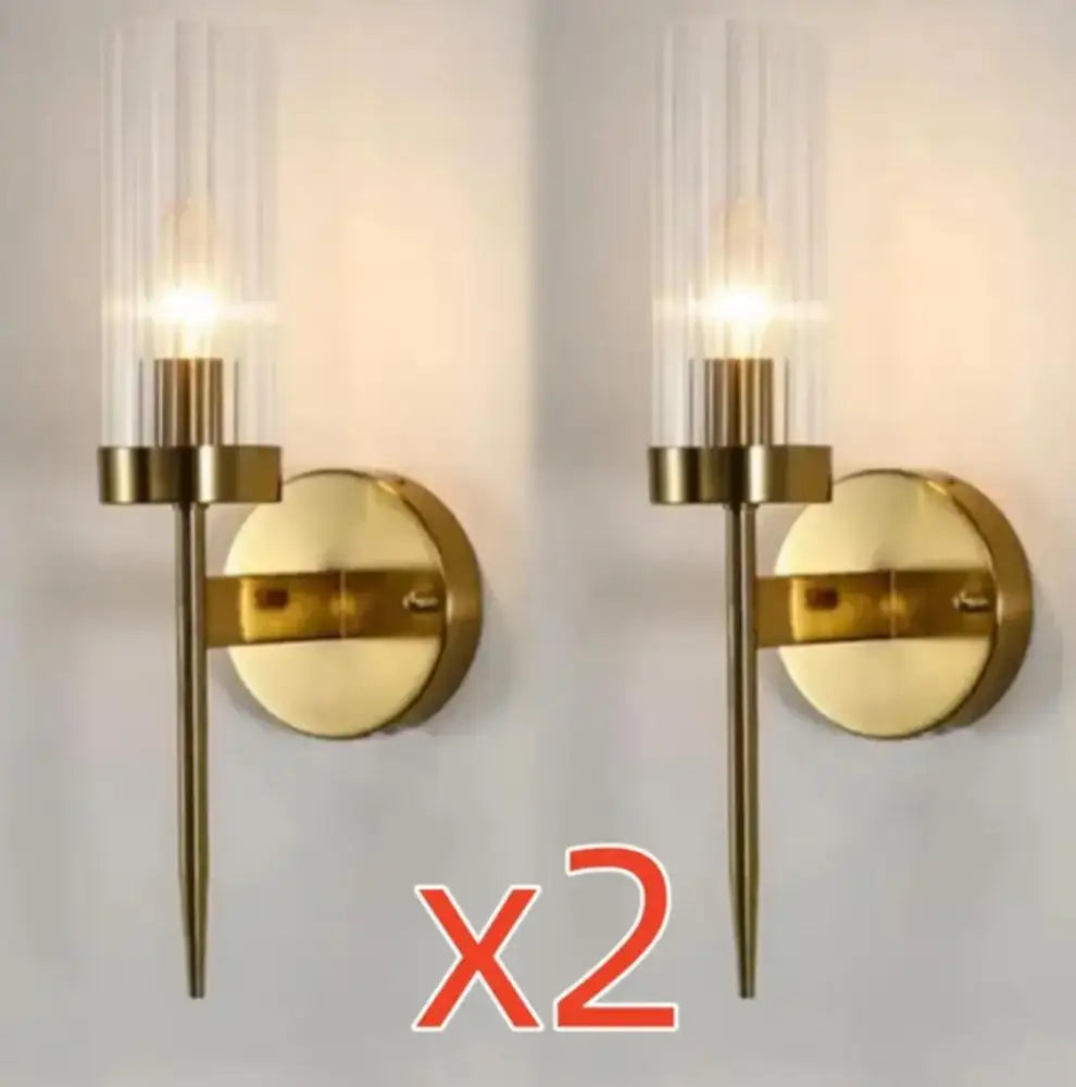 Gold-toned decorbites led sconce with cylindrical glass shade and slender metal stem for modern bedroom lighting