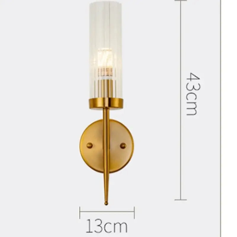 Gold-toned decorbites led sconce with cylindrical frosted glass shade and vertical ridges for modern bedroom use