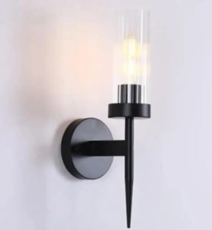 Black metal decorbites led sconce with clear glass cylinder housing illuminated bulb for modern bedroom lighting