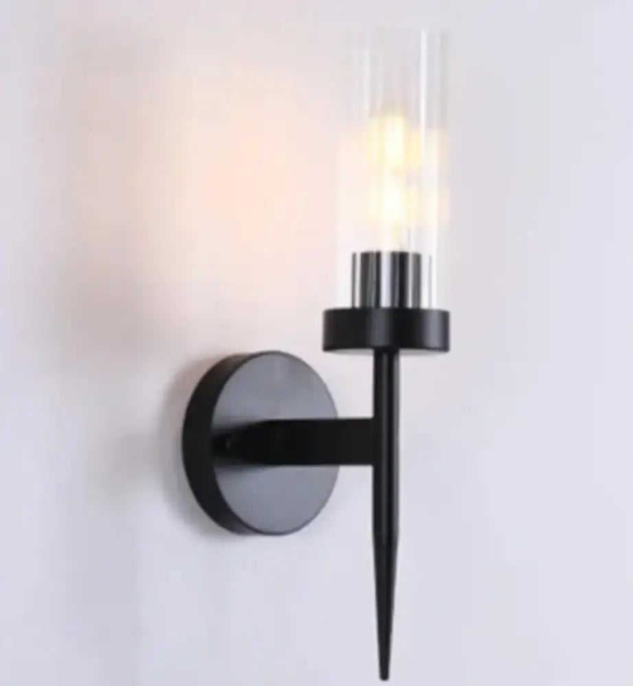 Black metal decorbites led sconce with clear glass cylinder housing illuminated bulb for modern bedroom lighting