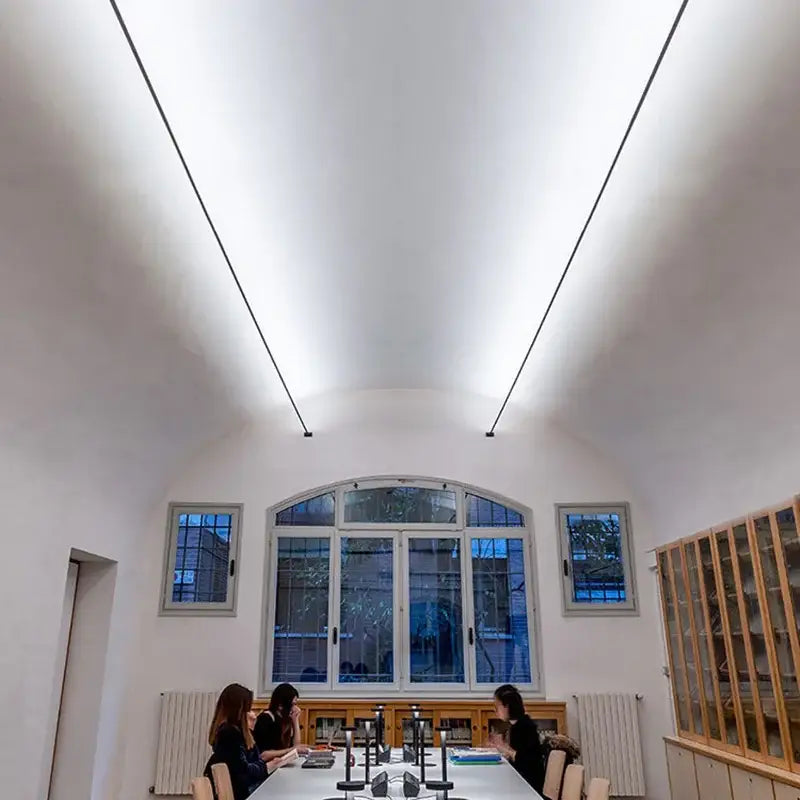 A modern conference room illuminated by decorbites led skyline linear wall light with minimalist design and large arched windows