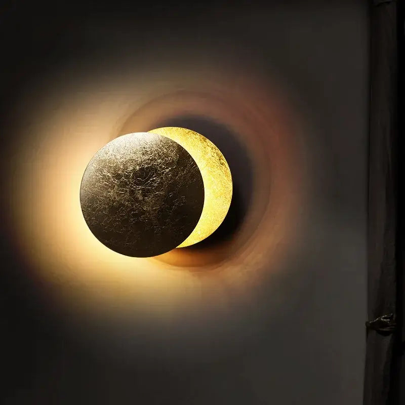 Warm-toned decorbites led solar eclipse wall lamp with dual-faced textured dark surface and glowing golden crescent light