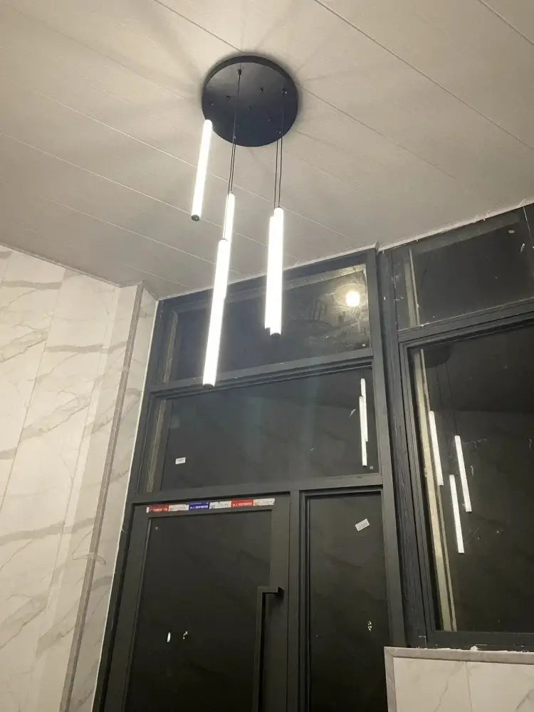 Modern black circular DecorBites™ LED spiral staircase chandelier with three vertical white LED light tubes for home décor