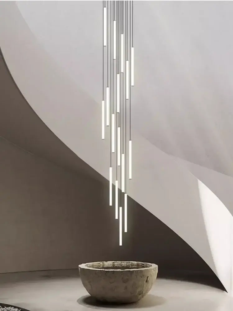 A modern minimalist led spiral staircase chandelier with slender cylindrical tubes in a sleek silver finish