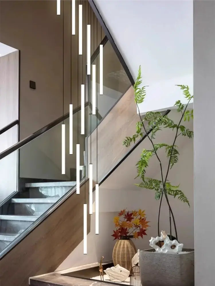 Modern white cylindrical led spiral staircase chandelier pendant lights hang in a staggered arrangement from the ceiling