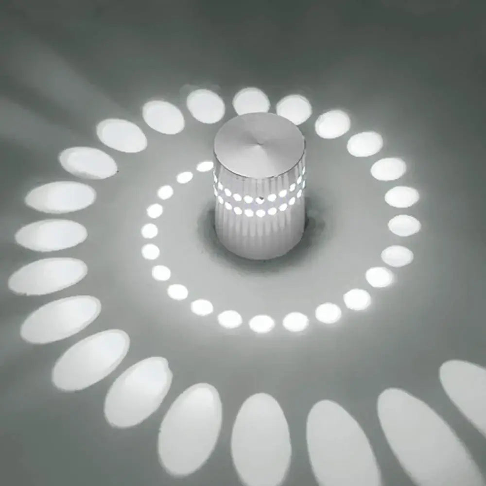 A sleek silver cylindrical DecorBites LED spiral wall light with textured surface casting an elegant spiral glow