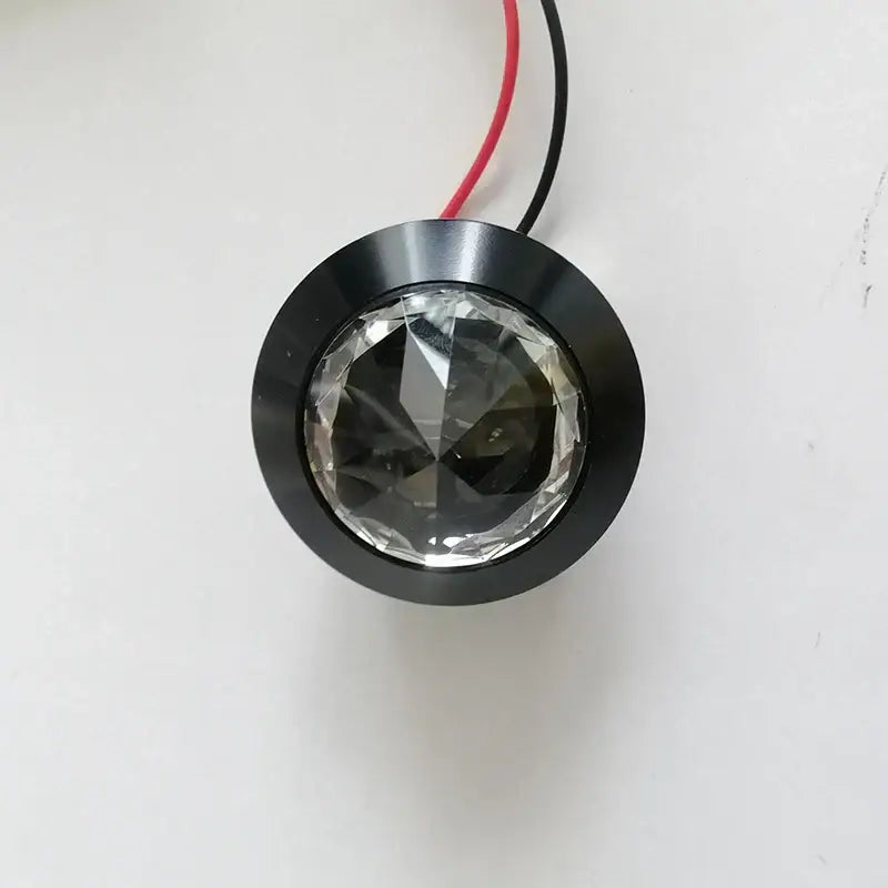 Black circular DecorBites LED spot with clear faceted crystal center and red black wiring for home and jewelry cabinet use