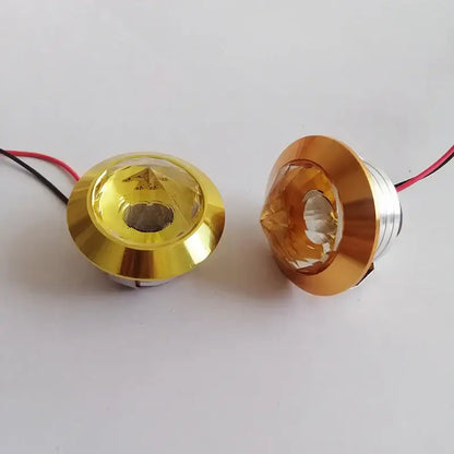 Two gold-finished decorbites led spot light fixtures with faceted crystal lenses and attached wiring for cabinet use