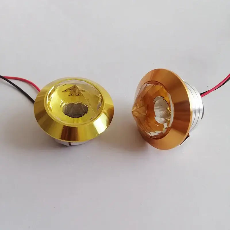 Two gold-finished decorbites led spot light fixtures with faceted crystal lenses and attached wiring for cabinet use
