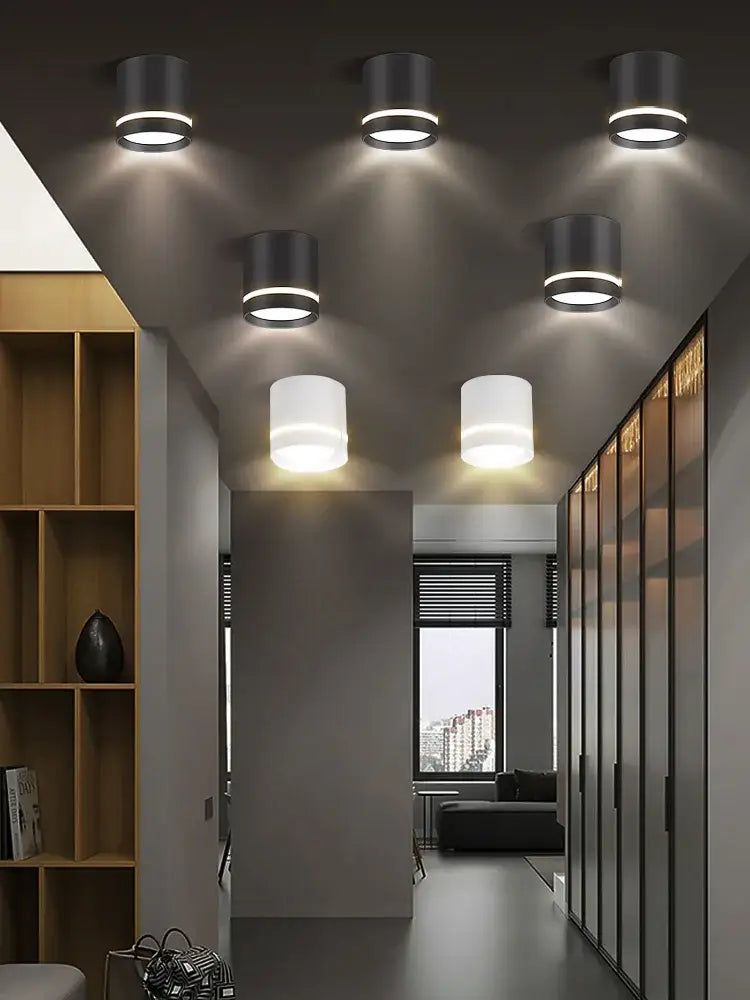 Six matte black cylindrical decorbites led spot ceiling downlights with frosted shades illuminate a modern hallway