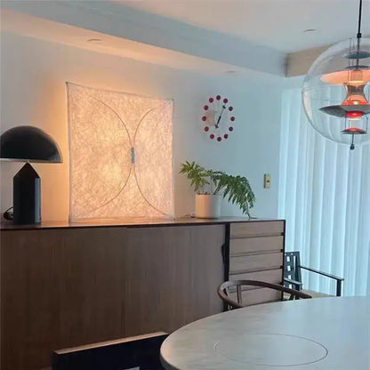 A modern black DecorBites LED square fabric wall lamp with minimalist design on a wooden cabinet for living room use