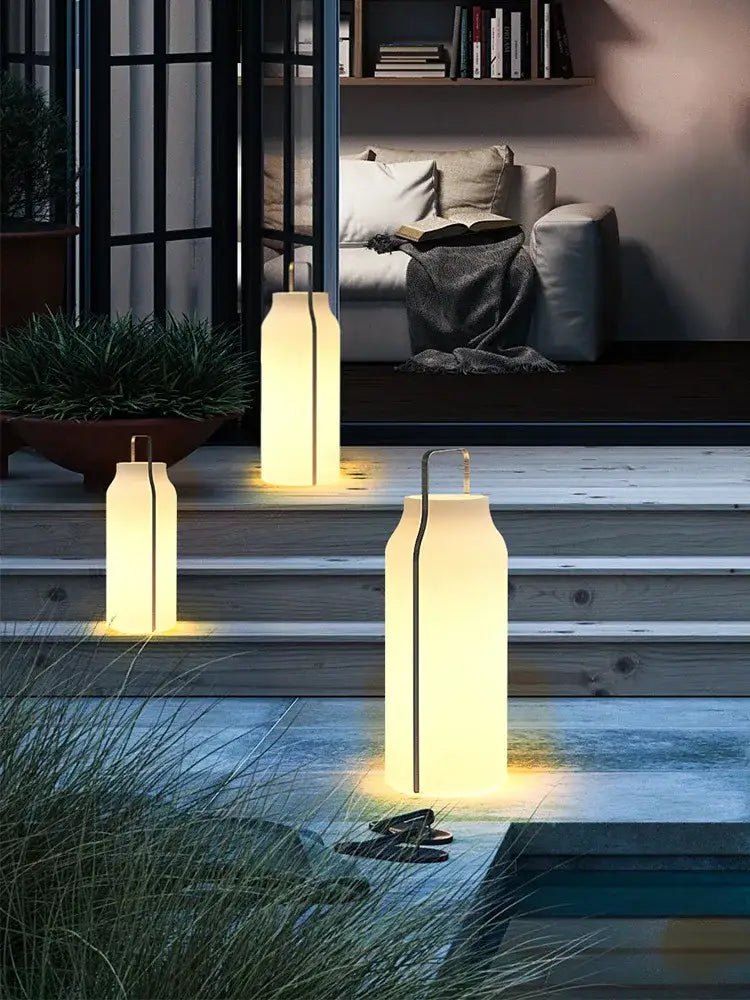 Three illuminated decorbites led stainless steel lawn lights with cream translucent panels and black vertical accents