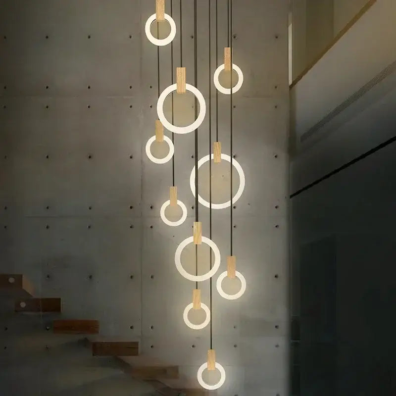 Modern minimalist DecorBites LED stair chandelier with glowing circular rings, black cords, and wooden accents for bedrooms