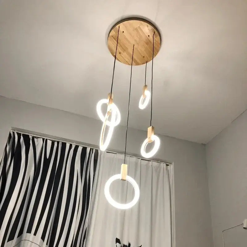 Modern circular decorbites led stair chandelier with light wood ceiling plate and four glowing rings suspended by black cords