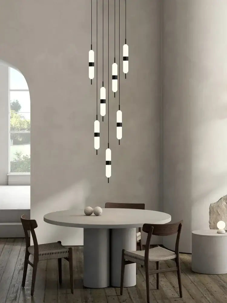 Modern minimalist decorbites led staircase chandelier with cylindrical glass shades and black metal accents for dining space